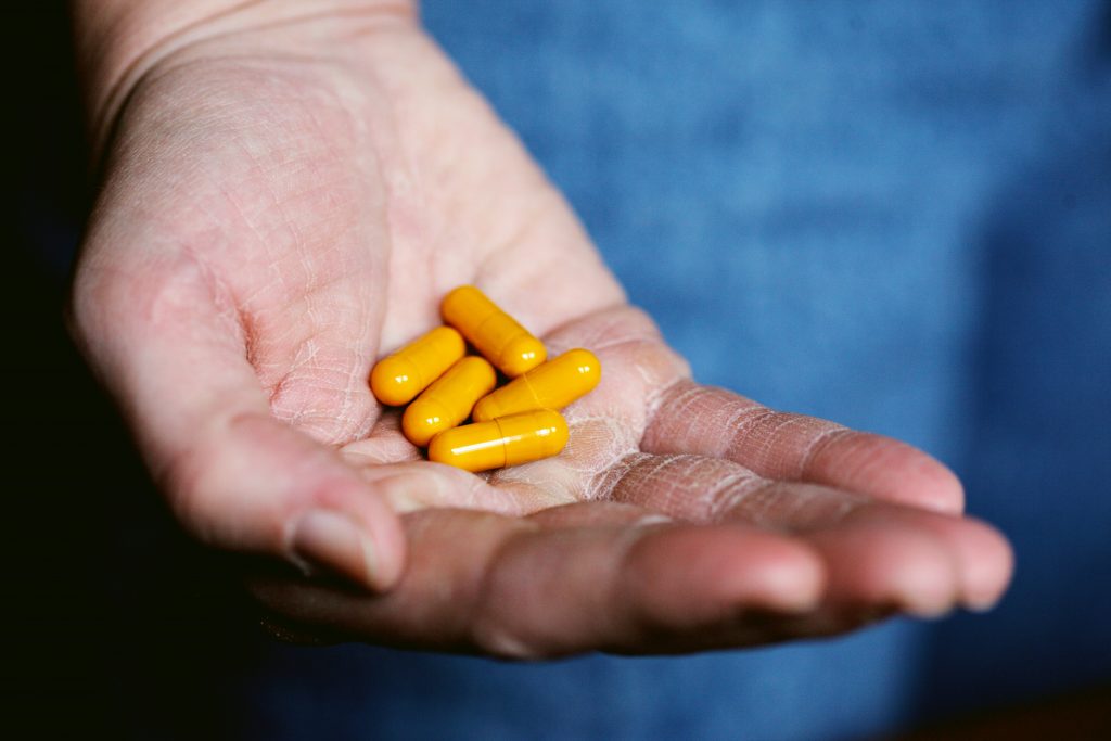 An image of a hand holding some yellow pills.