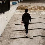 A man in a black suit walking purposefully up a concrete slope