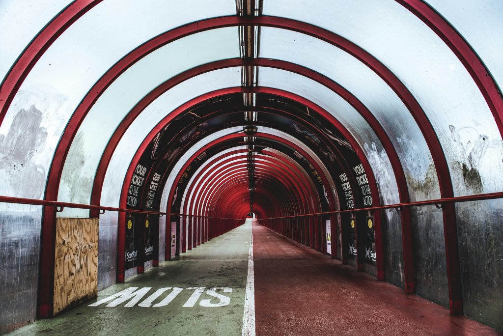 View up and enclosed tunnel with a slow sign painted on the ground.