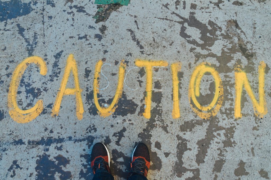 Caution is written on a pavement beside two feet