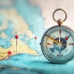 Magnetic compass  and location marking with a pin on routes on world map. Adventure, discovery, navigation, communication, logistics, geography, transport and travel theme concept background.