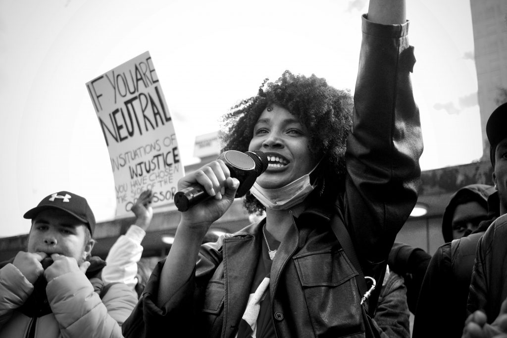 Picture of a Black female activist smiling and speaking into a microphone.